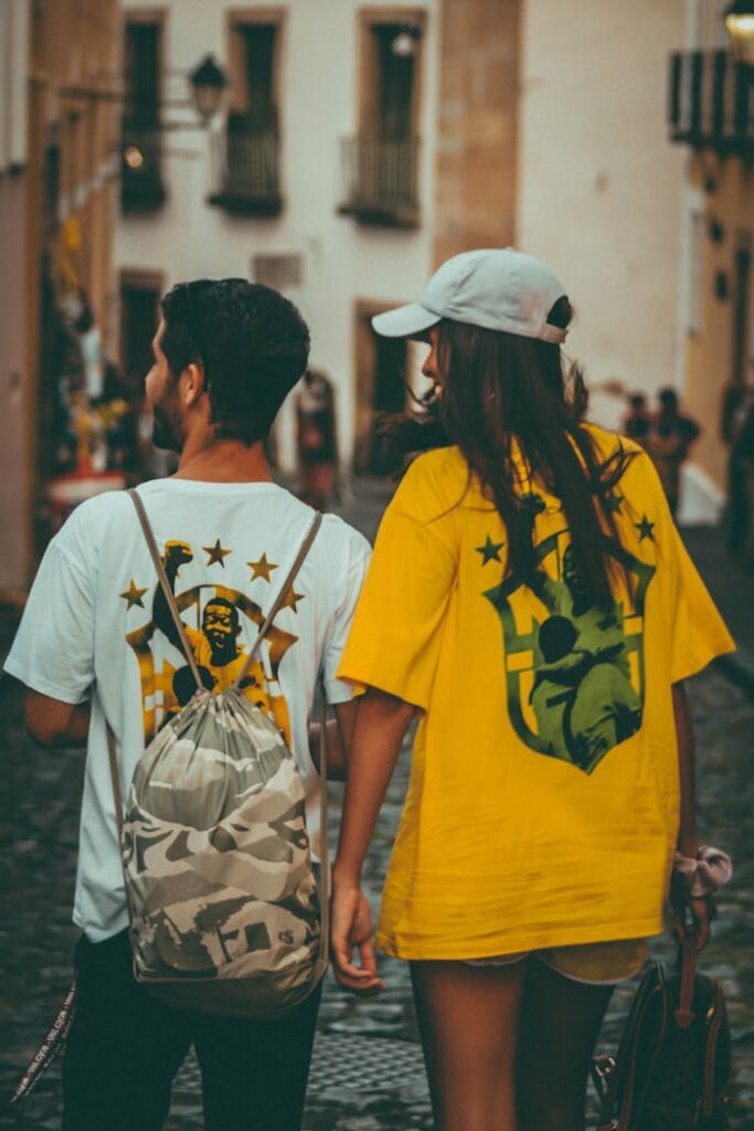 pexels photo 14122245 Young couple wearing colorful shirts, walking in city street. Urban lifestyle setting.