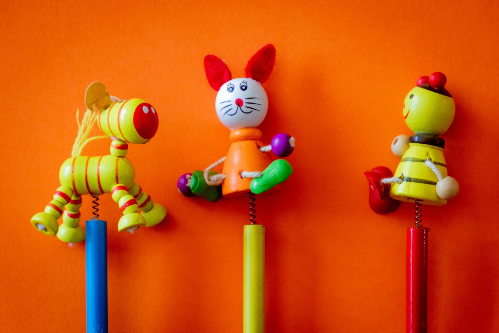 Dia das Crianças: 5 brinquedos que mudaram a história Brinquedos de madeira coloridos sobre fundo laranja, celebrando o Dia das Crianças